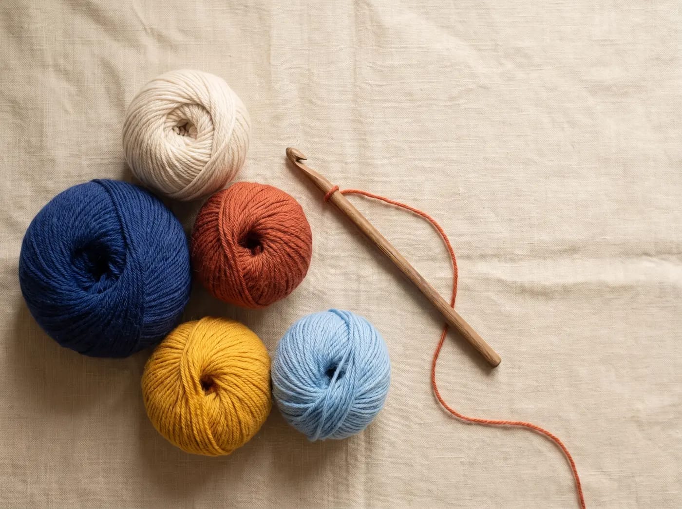Five balls of wool in the brand colours: indigo, ecru, terracotta, saffron and sky blue